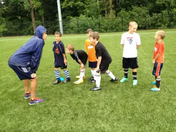 Coach training youth soccer players outdoors